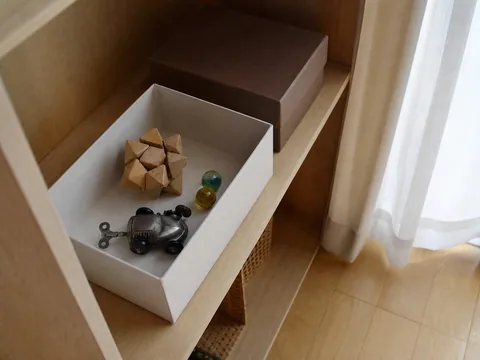 日本の住まいの収納箱に置かれた木製玩具と金属玩具、ガラス玉のイメージ